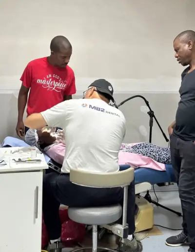Dental professionals examining patient in clinical setting with medical equipment present.