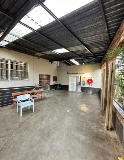Spacious dental clinic waiting area with concrete floor, skylights, and minimalist furnishings.