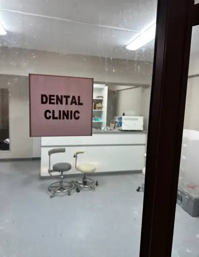 Empty dental clinic interior with reception desk and pink signage.